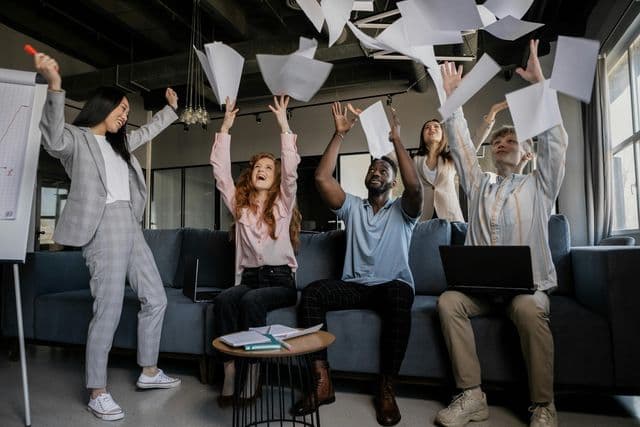 team members throwing papers up and laughing